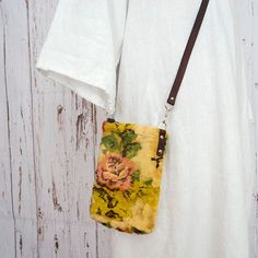 a small purse hanging on a white wooden wall with a t - shirt underneath it