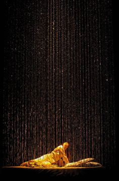 a person laying down in front of a rain shower with yellow lights hanging from the ceiling