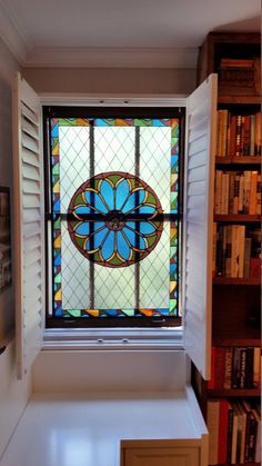 a stained glass window in the corner of a room with bookshelves behind it