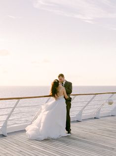 a bride and groom kissing on the deck of a cruise ship in front of the ocean