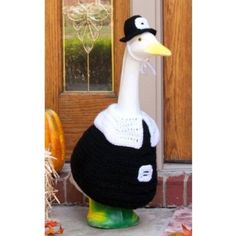 a fake duck is standing in front of a door with a hat on it's head