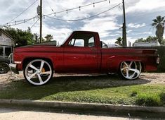 a red truck parked on the side of a road next to a building and power lines