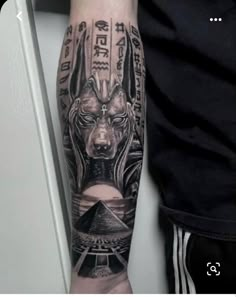 a man with a black and grey tattoo on his arm is wearing an egyptian mask