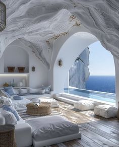 a bedroom with white walls and wooden floors, overlooking the ocean from an arched window