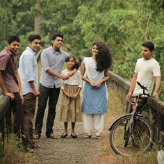 a group of people standing next to each other on a dirt road near a forest