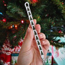 a person holding up a piece of string in front of a christmas tree