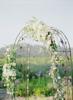 an arch decorated with white flowers and greenery