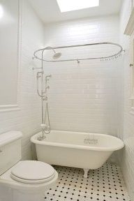 a white bath tub sitting next to a toilet under a skylight in a bathroom