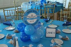 a table with blue and white plates, silverware and balloons