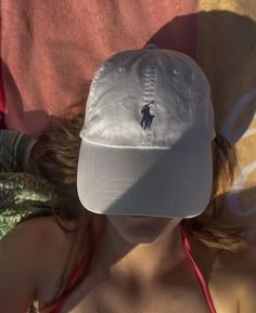 a woman wearing a white hat laying on top of a bed next to a blanket