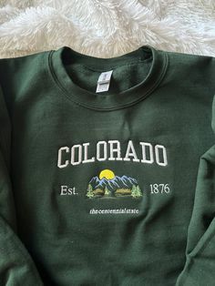 Colorado, stand up! Comfy sweatshirt with Colorado in a varsity-like font featuring a mountain design. This pullover Crewneck will keep you stylish and warm with its fleece lined fit.  You can add names on the sleeve for $5 extra!  This sweatshirt is available in 6 colors:  ✨ Military Green ✨ Forest Green ✨ Sand ✨ White (words will be in black) ✨ Light Blue ✨ Navy ✨ Heather Gray If there is a color you have in mind other than the ones available, send me a message and I can help! -Sweatshirt bran Colorado Cool Gifts, Cheap Women's Sweatshirt For College, Cheap Gray Sweatshirt For College, Trendy Cheap College Sweatshirt, Cheap Cozy College Sweatshirt, Cheap College Sweatshirt With Sublimation Print, Cheap Crew Neck Sweatshirt For Adventure, Cheap Green Outdoor Sweatshirt, Cheap Fleece Sweatshirt With Embroidered Graphics