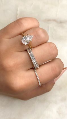 a woman's hand holding an engagement ring with two diamonds on top of it