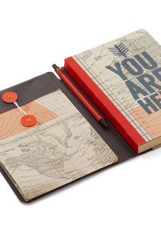 an open notebook with a red pen on top of it and a map in the middle