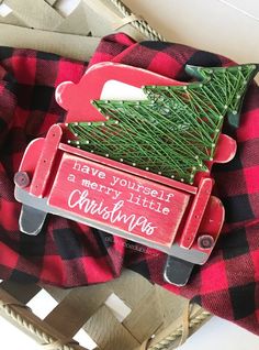 a red and black plaid christmas ornament with a tree on the back of it