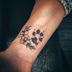 a dog's paw and flower tattoo on the left inner arm, with black ink