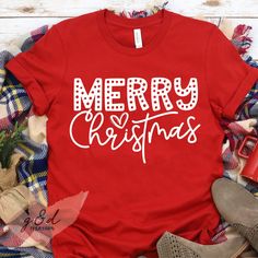 a red shirt that says merry christmas with white letters on it, surrounded by plaid fabric