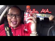 a man in a car holding up a bottle with the words hello, aia on it