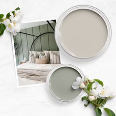 two paint cans with white flowers in them next to a photo of a bed and pillows