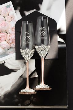 two wine glasses with the bride and groom's names on them are sitting next to each other