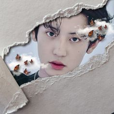 a man with blue eyes looking through a hole in the wall that has butterflies on it