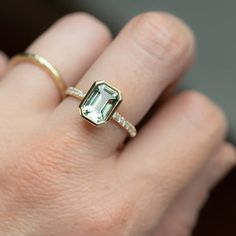 a woman's hand with a ring on it and an emerald stone in the middle