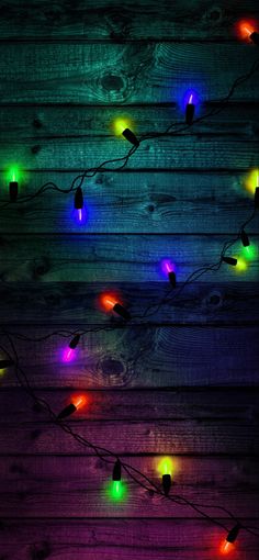 colorful lights are hanging on a wooden wall in the dark, and there is no image here to provide a caption for