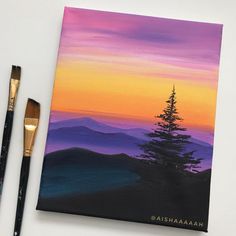 an acrylic painting of a pine tree in the mountains at sunset with paintbrushes next to it