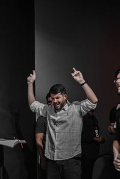 two men standing next to each other with their arms in the air and one man holding his hand up