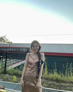 a young woman standing on top of a wooden bench next to a metal fence and green grass