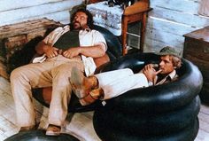 two men sitting on bean bag chairs talking on their cell phones in the living room