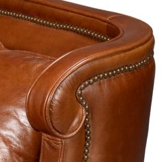 the back end of a brown leather chair with nail studded arms and footrests