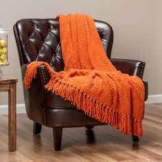 an orange blanket sitting on top of a brown chair