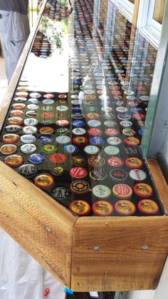 a wooden table topped with lots of different types of beer bottle cap display cases next to each other