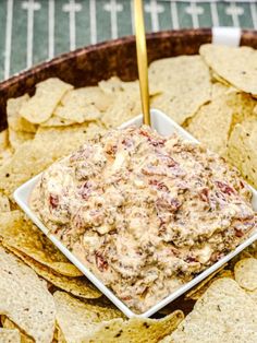 a bowl filled with dip surrounded by tortilla chips