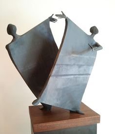 a metal sculpture with two people holding each other's arms