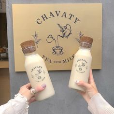 two people holding empty bottles in front of a sign that says chavaty tea and milk