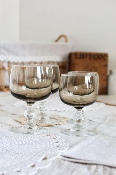 two wine glasses sitting on top of a table next to an empty basket and napkin