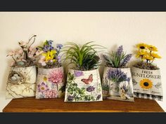 four flower pots with flowers in them sitting on a shelf