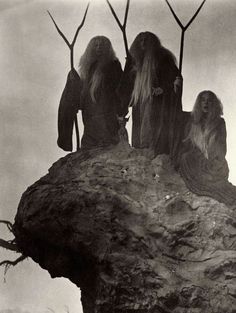 three long haired women sitting on top of a rock