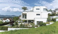 a white house with lots of windows sitting on top of a lush green hillside