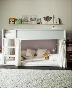 a white bunk bed with curtains on the top and bottom is next to a rug