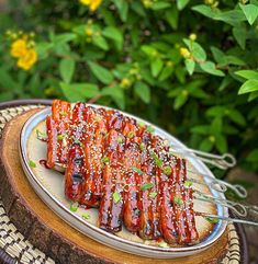 there are many barbecues on the plate with tongs next to it and flowers in the background