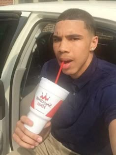 a young man drinking from a straw in his car