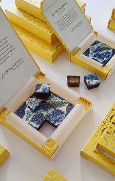 some yellow and blue boxes with chocolates in them on a white tableclothed surface