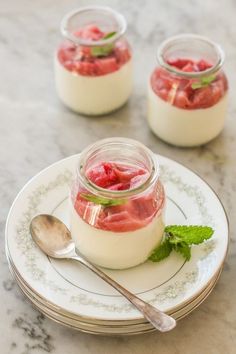 two jars filled with yogurt and strawberries on top of a white plate