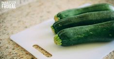 three green cucumbers sitting on top of a cutting board