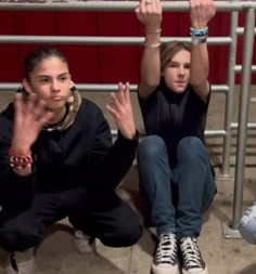 two women sitting on the ground with their hands up