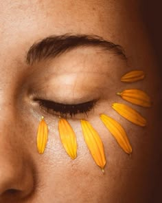 a woman's face with yellow flowers painted on her eyes