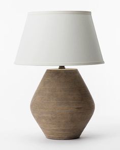 a table lamp with a white shade on it's base and a light bulb in the shape of a vase