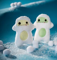 two small white stuffed animals standing next to each other on top of snow covered ground